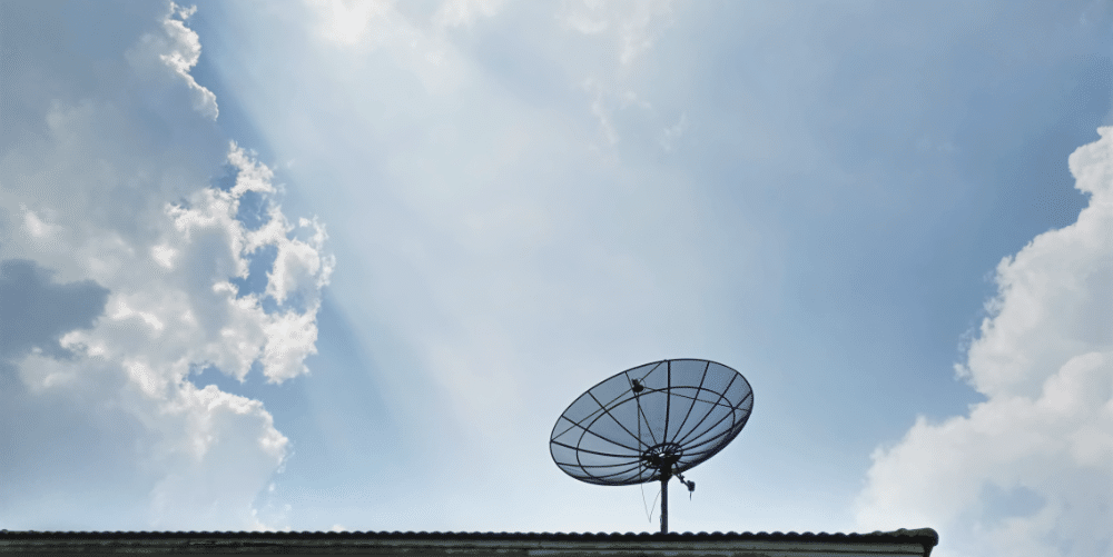 Satellitenschüssel auf Dach unter blauem Himmel